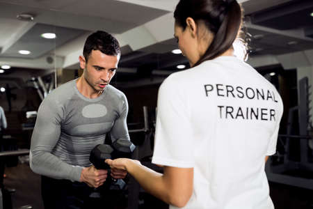 Female trainer doing workout with her client at gymの写真素材