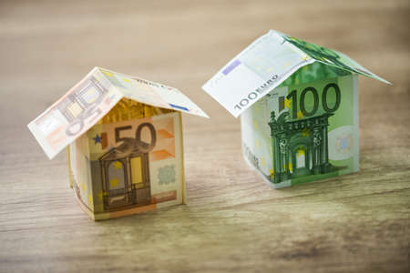 Money houses built of euro banknotes on wood backgroundの写真素材