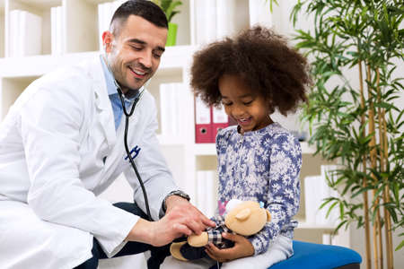 Doctor pediatrician playing and relaxing his patient before examiningの写真素材