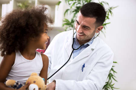 Positive pediatrician doctor examining cute kidの写真素材