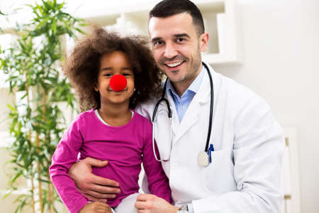 Funny little girl patient with pediatrician in officeの写真素材