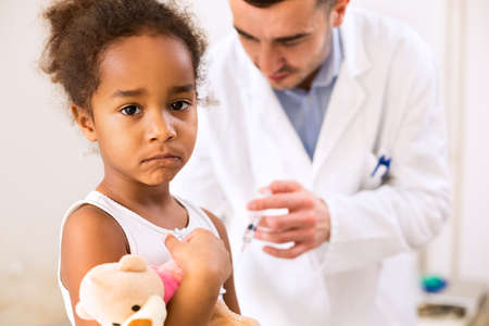 Sad little afican girl get an injection in armの写真素材