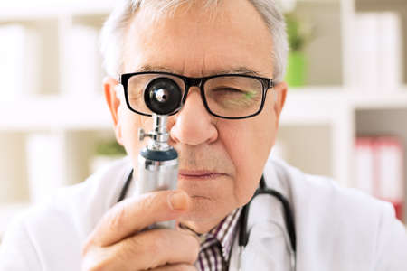 Otolaryngologist specialist looking through otoscopeの写真素材