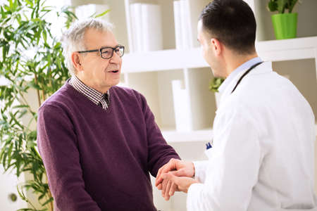 Young doctor holding hand and relaxing old patientの写真素材