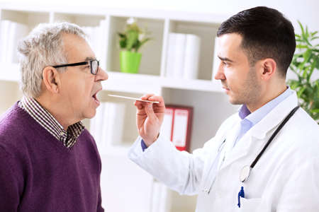 Doctor examining old patient sick throatの写真素材