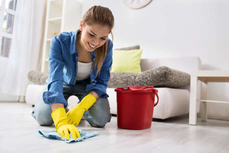 Smiling girl wash the floor with rag and detergent