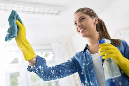 Smiling wife washed the window with a cloth and detergentの写真素材