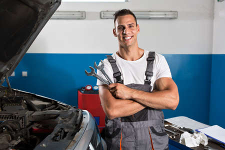 Satisfied and happy mechanic holding tools