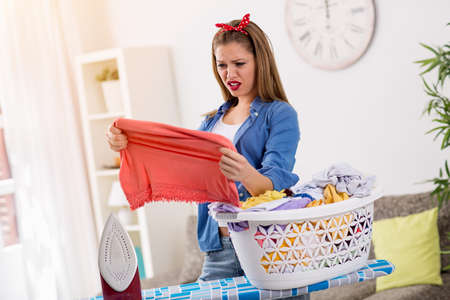 A young suprised housewife looking stain on clothesの写真素材