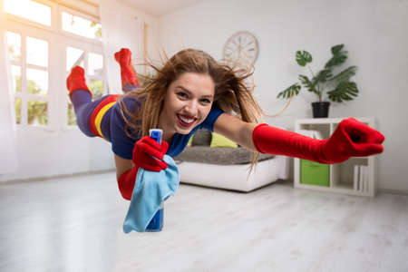 Attractive woman superhero flying through the room with a mopの写真素材