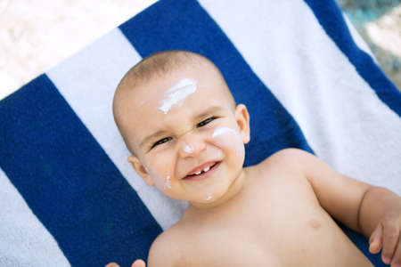 Suntan lotion on baby face at the beach