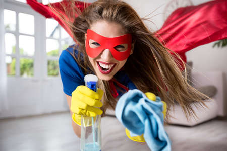 Woman superhero flying through the room with a mopの写真素材