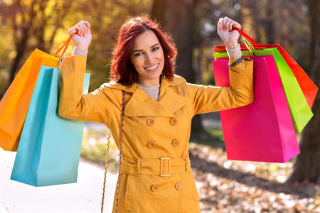 Smiling woman with colorful shopping bags, autumn conceptの写真素材