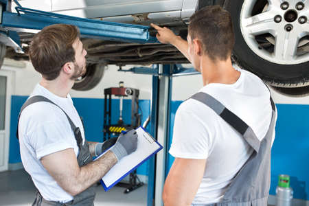 Auto workshop mechanics inspecting damage to a car