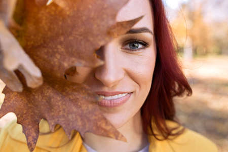Smiling girl hides behind the leaf, autumn portraitの写真素材
