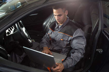 Professional car mechanic working in auto repair service, diagnostic timeの写真素材