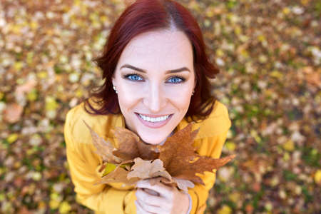 Autumn portrait of a smiling girl, happy and smiling girl holding leaves