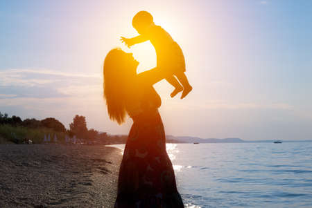 Happy lovely family mother and child son on beach at sunsetの写真素材