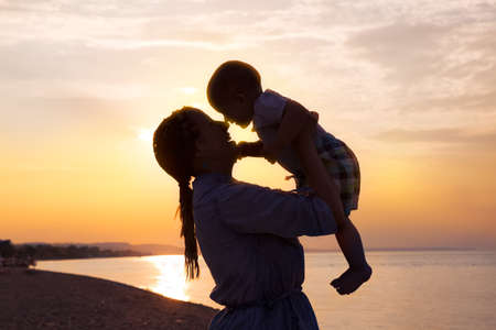Happy lovely family mother and child son on beach at sunsetの写真素材