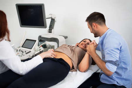Pregnant smiling woman and the future father waiting ultrasound picture of baby
