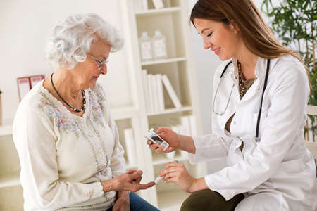 Young female doctor making diabetes blood test on senior woman, closeupの写真素材