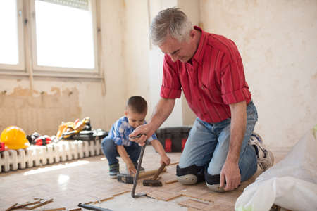 Grandson is helping to his grandfather in separating the old parqet, at homeの写真素材