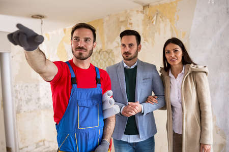 Handyman shows to young couple details about renovations their houseの写真素材
