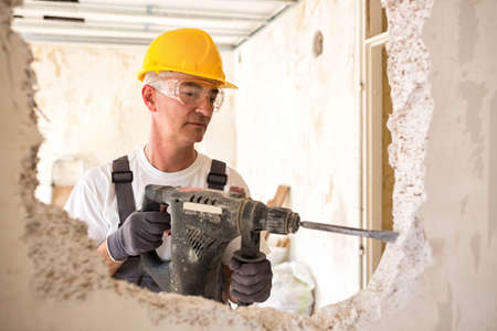 Senior worker using drill at contruction site, closeupの写真素材