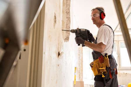 Senior worker using drill at contruction site, closeupの写真素材