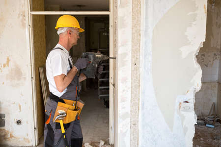 Senior worker using drill at contruction site, closeupの写真素材