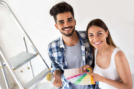 Young smiling happy couple choosing colors for painting their homeの写真素材