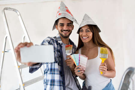 Attractive couple taking selfie while painting homeの写真素材