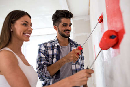 Lovely smiling happy couple painting new home, new house renovationの写真素材
