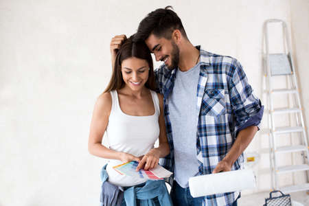 Young happy smiling couple choosing colors for painting their home