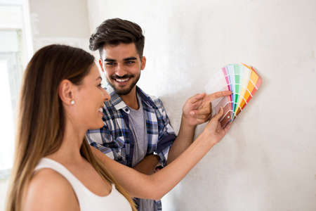 Young happy smiling couple choosing colors for painting their homeの写真素材