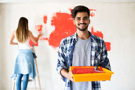Young happy couple decorate their new apartment.They painting new homeの写真素材
