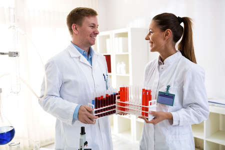 Two chemists holding tubes and talking about laboratory jobの写真素材