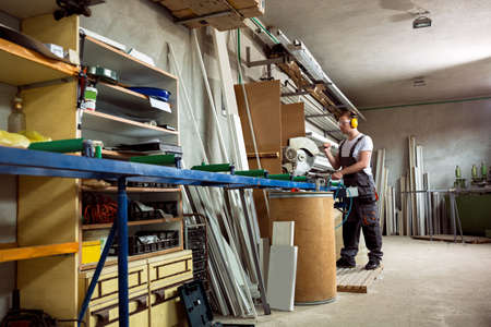 Worker in the workshop cuts the pvc profile with circular saw