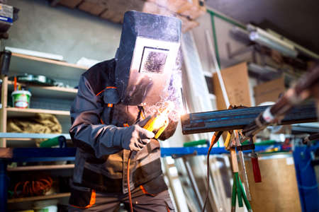 Welder working in workshop while wearing protective gearの写真素材