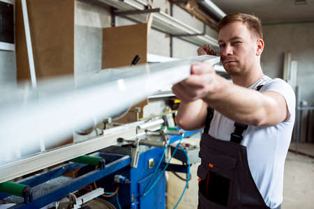 Worker measures and prepares pvc profiles in the workshop for window and door manufacturingの写真素材