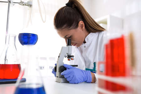 Lab technician working on microscope doing research with lab samples