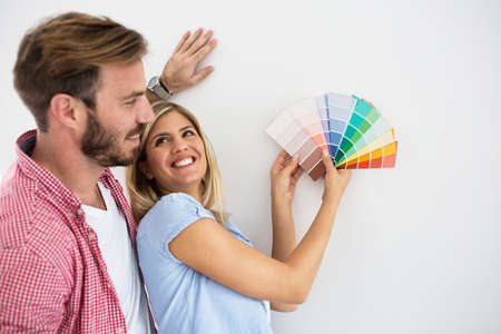 Young happy couple choosing colors for painting their homeの写真素材