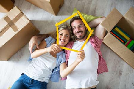 Attractive young couple relax between boxes on floor at new apartment, moving conceptの写真素材