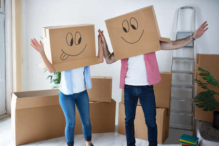 Funny happy couple sitting on floor wearing smiley cardboard boxes
