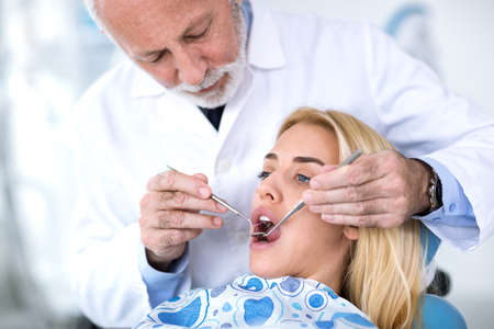 Senior dentist  reviews patient  teeth at  dentist's clinic