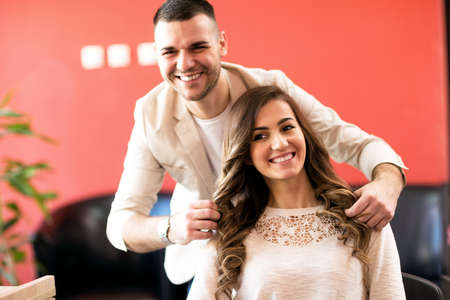 Smiling hairsyilist and his satisfied client at beauty salonの写真素材