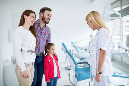 Young female dentist encourages family in dental officeの写真素材