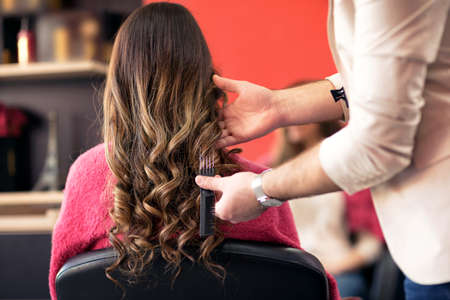 Male hairdresser styling clients hair at beauty salon
