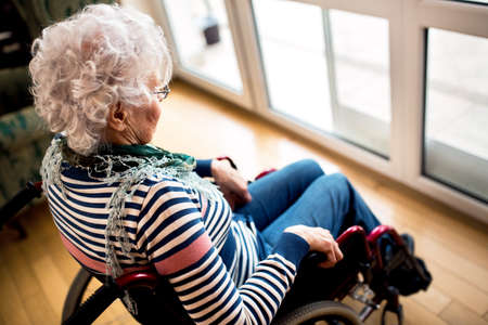 Sad depression loneliness senior woman in wheelchair at nursing home