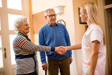 Smiling positive nurse shake hands with new patients at private clinicの写真素材